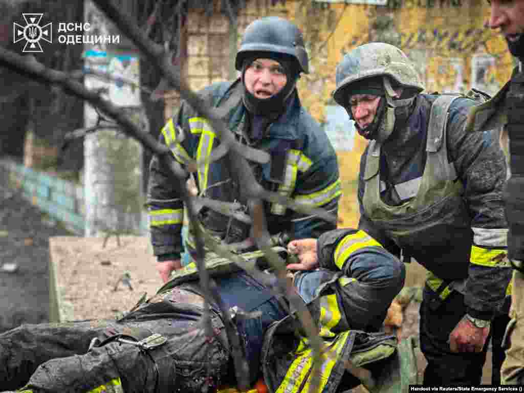 Рятувальники виносять пораненого колегу з місця ракетного обстрілу в Одесі.15 березня 2024 року. Рятувальники, які прибули на місце російського ракетного удару в Одесі, де розпочалася пожежа, загинули внаслідок другого ракетного удару, завданого Росією по тому самому місці. За словами офіційних осіб, серед щонайменше двох десятків загиблих через російську ракетну атаку вдень 15 березня – були цивільні, фельдшер і рятувальник ДСНС.