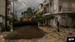Местен жител стои до булдозер, който почиства кална улица след бурята "Елиас" във Волос.