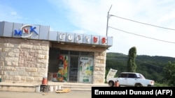 Nagorno-Karabakh - An abandoned vehicle is parked in front of a closed shop in Stepanakert during an Azeri government organized media trip, October 2, 2023. 