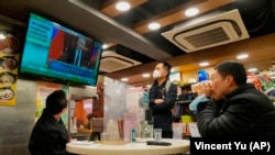 Ljudi gledaju TV prenos vijesti o napadu ruskih vojnika na Ukrajinu u restoranu u Hong Kongu 24. februar 2022. 
