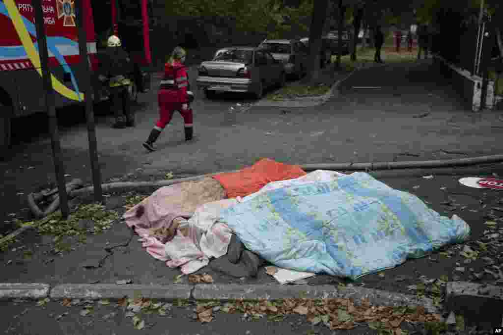 Загиблі внаслідок російського ракетного обстрілу цивільні люди на вулиці Дніпра. Російська армія запустила по українських містах 75 ракет у ранкові години, коли люди їхали на роботу, відводили дітей у дитсадки та школи. 