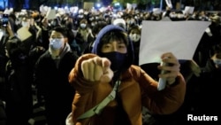 Manifestantlar protest alamaty bolan ak kagyzy elinde tutup durlar, Pekin, 2022-nji ýylyň 27-nji noýabr agşamy