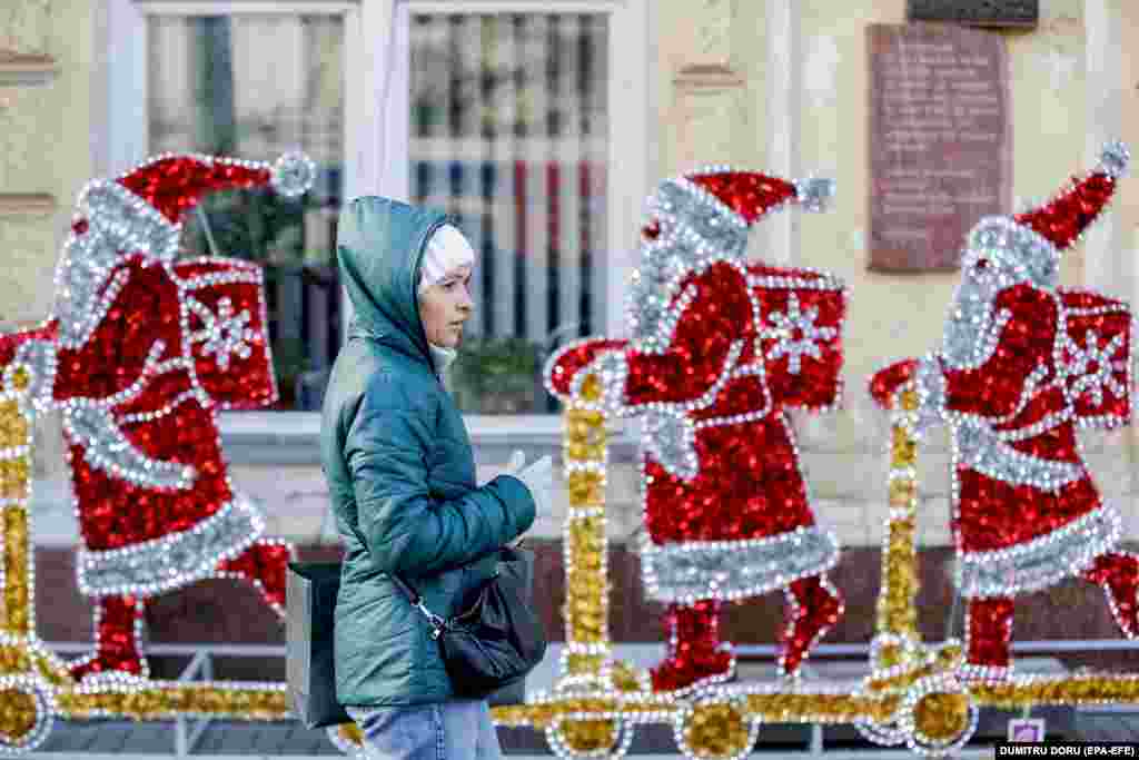 Молдова, Кишинев. Рождество майрамына карата жасалгалардын жанынан өтүп бараткан аял. 