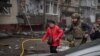 Украински војник евакуира жена од станбена зграда погодена од руски ракетен напад, Суми, 24 март 2025 година.