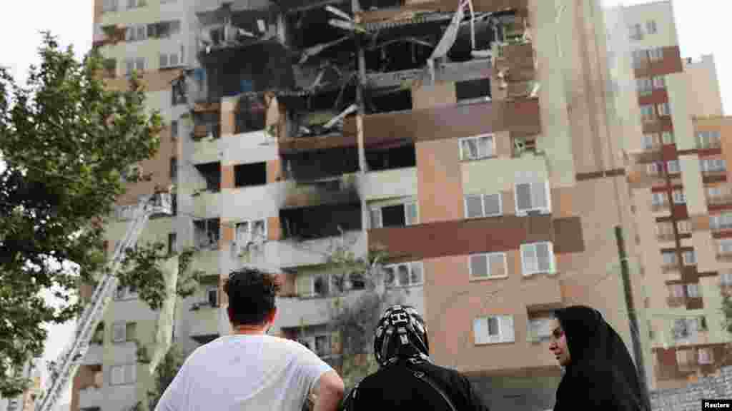 13-июнда Тегеранда Израилдин аба соккуларынан кийин жабыркаган имаратты карап турган адамдар.