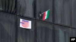 یک پوستر ضدآمریکایی در کنار پرچم جهوری اسلامی بر یک ساختمان دولتی در تهران، آبان ۱۴۰۲
