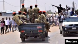 Sudanese antigovernment protesters cheer as they drive towards a military vehicle after Sudan's defense minister said that President Omar al-Bashir had been detained "in a safe place" and that a military council would run the country.