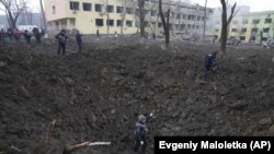 Українські рятувальники і військові на території знищеної російськими обстрілами лікарні в Маріуполі, 9 березня 2022 року