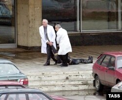 Медики тягнуть тіло людини, яка загинула після застосування газу