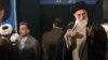 Iran's supreme leader Ayatollah Ali Khamenei, right, escorted by bodyguards greets people as he attends a ceremony to commemorate the 11th anniversary of the death of Ahmad, seen in the picture in the background, son of late Iranian revolution leader Ayat