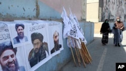 Afganistanke prolaze pored plakata talibanskih vođa i zastava u Kabulu, Afganistan, u avgustu 2021.