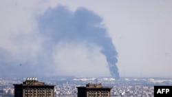 Smoke billows in the distance from an oil refinery following an Israeli strike on the Iranian capital Tehran on June 17, 2025.