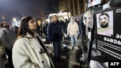 Žena u Tbilisiju gleda poster na kojem se vide ljudi koje je navodno pretukla gruzijska policija, 9. decembar 2024.