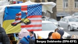 Українці проходять повз сувенірну лавку з прапором, на якому зображені символи України та США, центр Києва, 6 листопада 2024 року